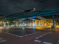 the empty street is filled with people walking and biking under an overpass at night