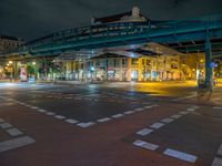 the empty street is filled with people walking and biking under an overpass at night