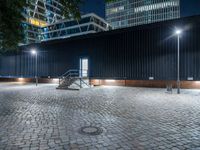 night scene in public parking area with lights on and steps up to building behind it