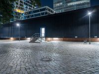 night scene in public parking area with lights on and steps up to building behind it