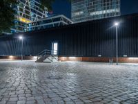 night scene in public parking area with lights on and steps up to building behind it