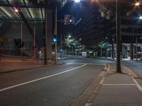 a road filled with lots of traffic next to tall buildings at night as it is mostly empty