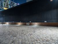 a black fence in front of a building at night with street lights and the building behind