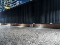 a black fence in front of a building at night with street lights and the building behind