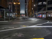 the city street at night is lit by headlights and lights on the buildings in the background