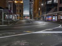 the city street at night is lit by headlights and lights on the buildings in the background