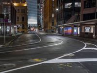 the city street at night is lit by headlights and lights on the buildings in the background