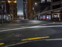 the city street at night is lit by headlights and lights on the buildings in the background