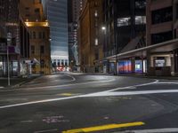 the city street at night is lit by headlights and lights on the buildings in the background