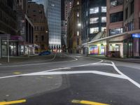 the city street at night is lit by headlights and lights on the buildings in the background