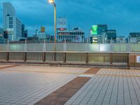 people standing on a subway platform with many buildings in the background at night light in tokyo