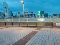 people standing on a subway platform with many buildings in the background at night light in tokyo