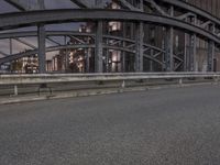 a car passing a bridge that is next to another building in the background with street lights in front of it