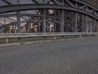 a car passing a bridge that is next to another building in the background with street lights in front of it