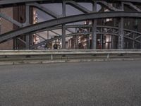 a car passing a bridge that is next to another building in the background with street lights in front of it