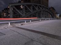 a car passing a bridge that is next to another building in the background with street lights in front of it