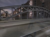 a car passing a bridge that is next to another building in the background with street lights in front of it