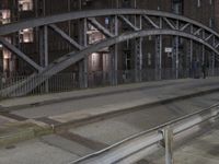 a car passing a bridge that is next to another building in the background with street lights in front of it