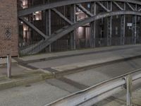 a car passing a bridge that is next to another building in the background with street lights in front of it