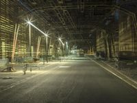 an empty long street with a car at the end of it at night time near a large factory