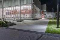 the empty courtyard at night outside an office building with glass walls and lots of lights