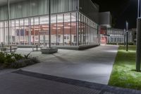 the empty courtyard at night outside an office building with glass walls and lots of lights