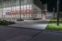 the empty courtyard at night outside an office building with glass walls and lots of lights