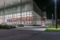 the empty courtyard at night outside an office building with glass walls and lots of lights