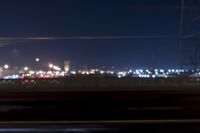 a blurry photo of an industrial area from a moving vehicle at night, with blurred power lines,