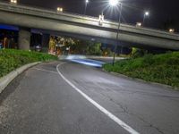 a street with a bridge over it that leads to the side of the road and lights on