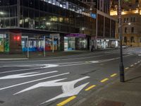 a city street at night with the lights on in a building behind it and on the ground at the intersection