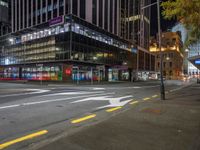 a city street at night with the lights on in a building behind it and on the ground at the intersection