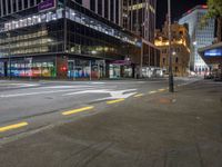 a city street at night with the lights on in a building behind it and on the ground at the intersection