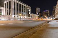 some buildings a street and some cars on the road at night time? in the city