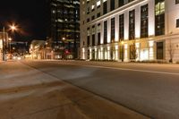 some buildings a street and some cars on the road at night time? in the city