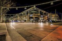 street scene at night with cars parked on a curb and illuminated trees on both sides