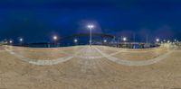 a full view of an empty parking lot and a bridge in the distance, at night