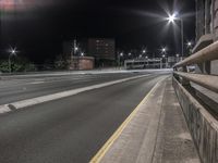 a view from a building onto an empty road at night, with multiple street lights in the background