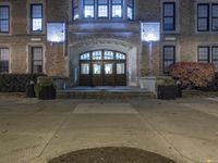 the entrance to an old brick school building at night, with lights on the front of it