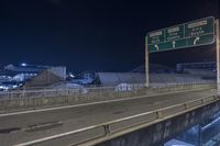 a freeway sign on the side of a road at night by a body of water