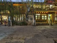 the view of people walking through the village at night time in the evening time, from the back of a house with wooden furniture