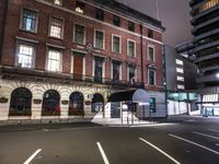 a bus stop on the street of a city at night with an umbrella attached to it