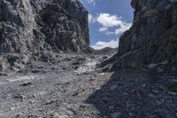 the person is standing in the rocky canyon with their suitcases on the ground next to them