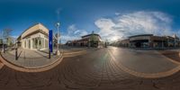 a fish eye lens shot of a street with stores and cars on both sides of it