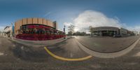 a fish eye view shows the city's intersection of a busy street with a flower lined shopping mall