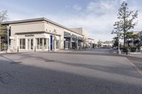 a view looking into an empty street from the corner with some shops and stores on either side