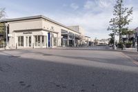 a view looking into an empty street from the corner with some shops and stores on either side