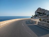 a long curved road going into the ocean with a motorcycle on it in front of it