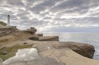 the ocean is calm as if it's on a rocky cliff beside the lighthouse