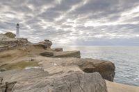 the ocean is calm as if it's on a rocky cliff beside the lighthouse